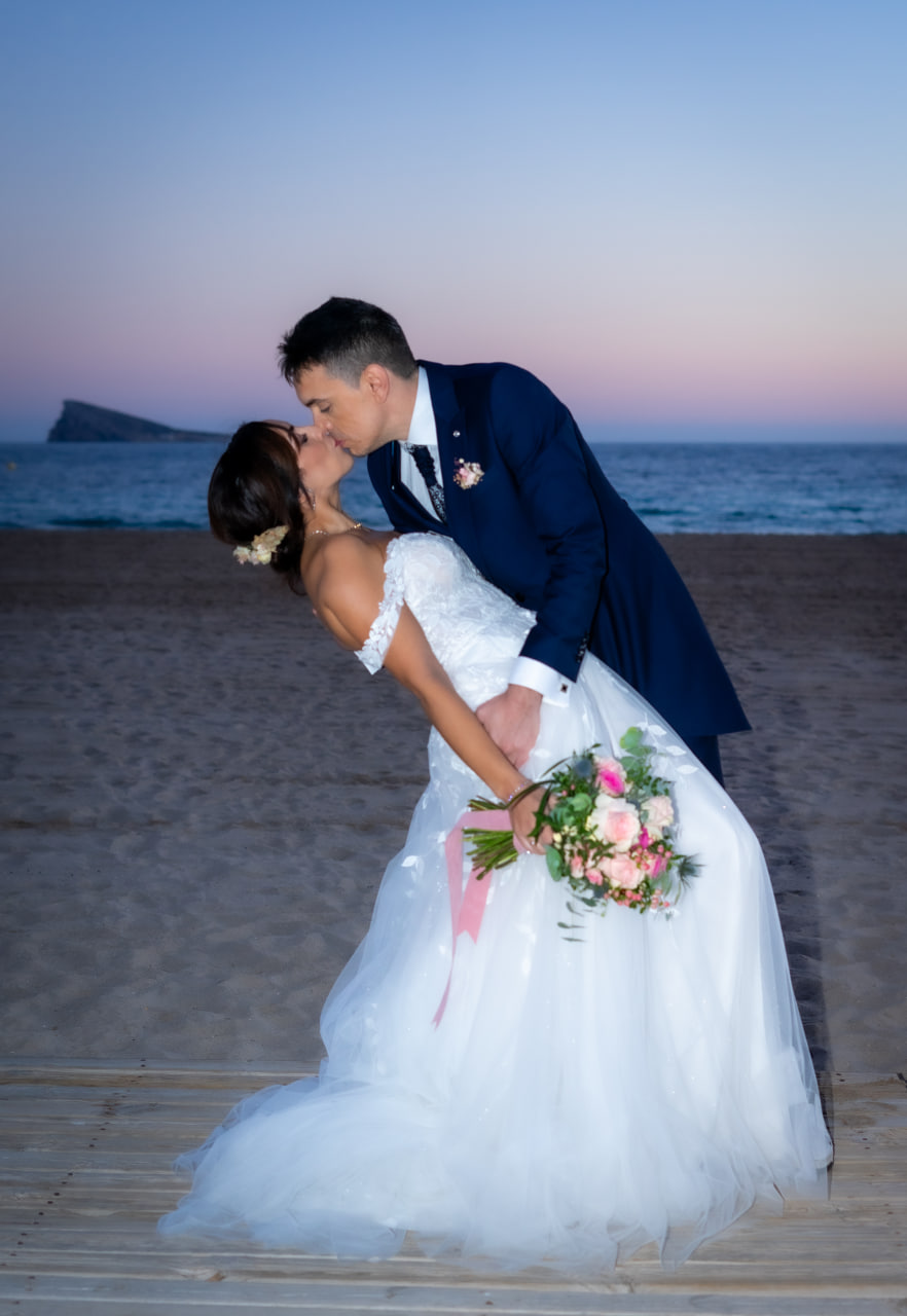 Beso de los novios en la playa al atardecer